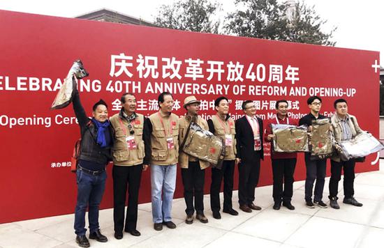 中国新闻摄影学会会长徐祖根(左三)、光明网总裁兼总编辑杨谷(右四)、中国新闻摄影学会副会长赵建伟(左二)、李景录(右五)向参加展览的主流媒体记者、作者发放学会官方摄影服