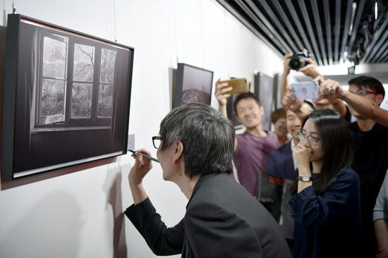 张亚东在自己的作品上签名，作品采用锌板特殊材质打印制作 周星宜 摄