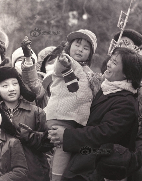 逛庙会的人们在一片树林旁的开阔地上看训鸟，摄于1985年2月。