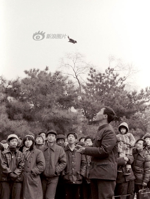 逛庙会的人们在一片树林旁的开阔地上看训鸟，摄于1985年2月。