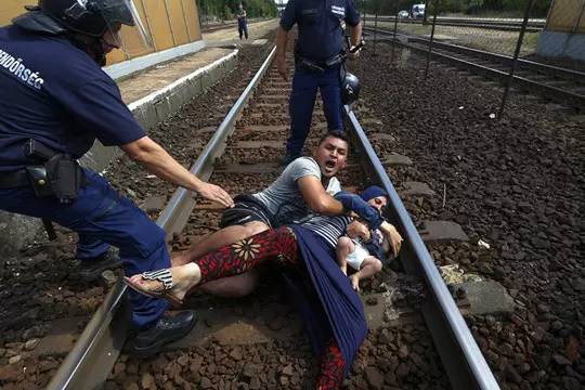 2015年9月3日，一名匈牙利警察将躺在铁轨上的移民拉上路边。摄影师：Laszlo Balogh