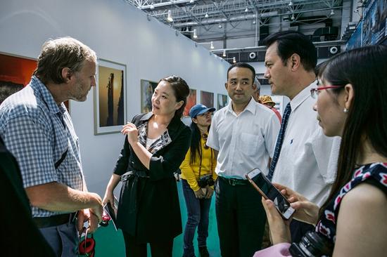 参展的德国摄影师卡斯滕·彼得（左一）与中国文联党组成员、副主席、书记处书记李前光（右二），伊春市副市长范庆华（右三），中国摄影出版社社长赵迎新（左二）在展览现场交流。