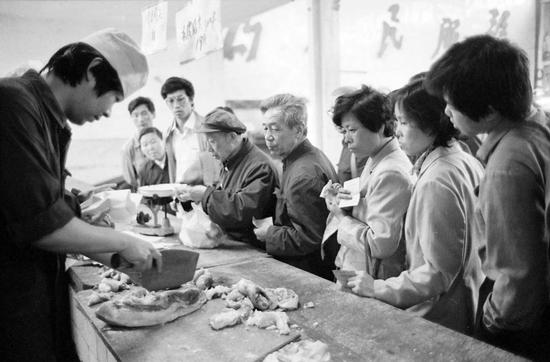 1988年5月15日早晨，北京市朝内菜市场大肉组售货员按原价定量供应生肉。市民纷纷涌入菜市场持北京市居民购货证和肉票排队抢购。