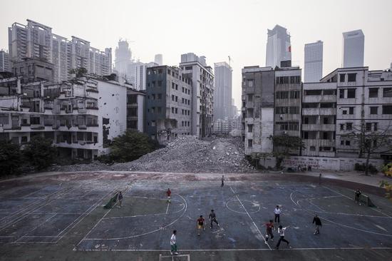 　　2014年1月14日傍晚时分，广州冼村处于拆迁停滞状态，村民们在一个小学废弃的篮球场上踢足球。  摄影：黎湛均