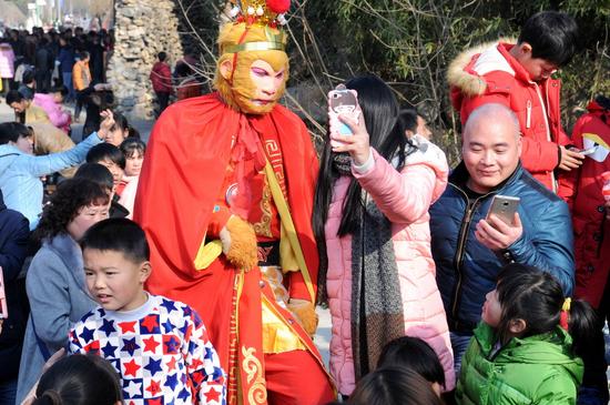 2016,02,28，河南驿城。春节期间，金顶山景区娱乐活动，周边村庄乡亲纷纷与孙悟空的扮演者合影。