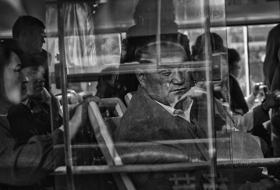 2009年，新疆75事件后，公共汽车上的一位乘客在向车窗外张望。