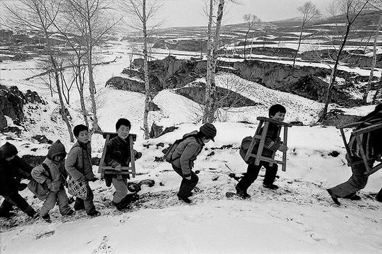 1992年3月，山西省静乐县赤泥洼乡羊丈村，扛着桌凳去上学。