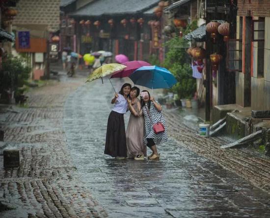 摄影师：王家能 ‘相机摄’湖南永州市零陵老街， 三位美女在雨中的老街玩自拍。