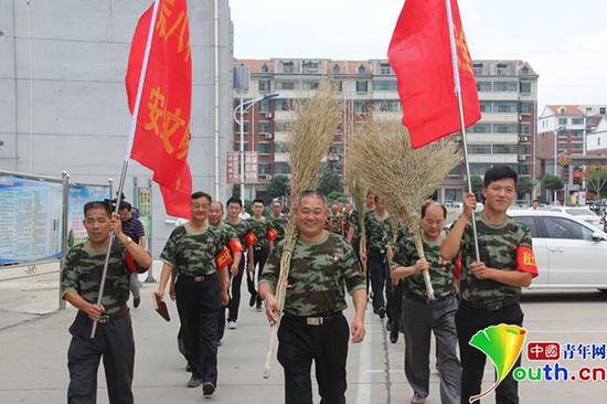 宋伟(中)带领村里退役军人组建志愿服务队，在辖区内打扫卫生（受访者供图）