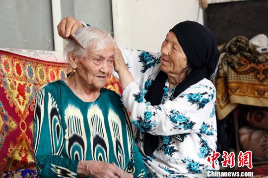 女儿塔吉古丽·吐尔地为母亲阿丽米罕·色依提梳头。 王小军 摄