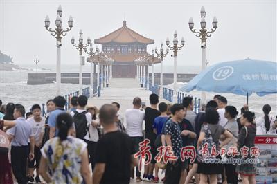 3日,栈桥及各海水浴场关闭。图为游客站在栈桥入口眺望波浪翻滚的景象。 邢志峰 摄
