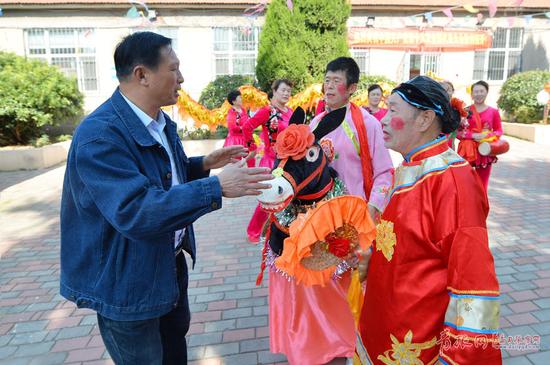 2017年10月22日,青岛市市北区闫家山,非遗闫家山地秧歌传承人闫恒臣(左)与表演者一起交流。