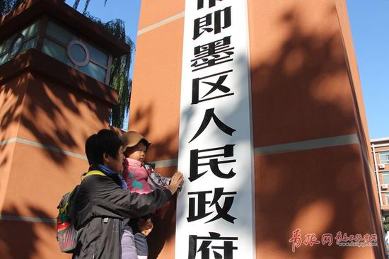 图为市民在青岛市即墨区人民政府门前拍照留念。