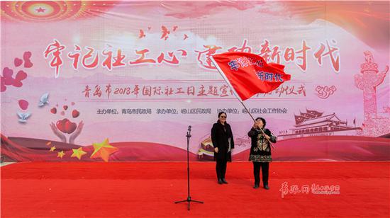 △图为向全国社会工作领军人才、和谐使者徐进授旗。