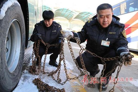 ▲汽车北站的检车人员正在与司机为改走国道省道的车辆安装防滑链