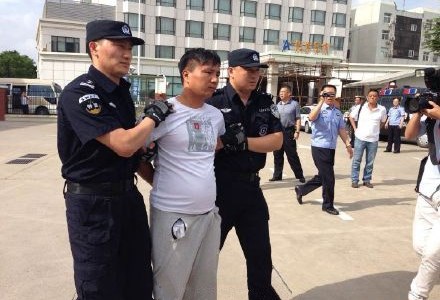 资料图片:李德彬被专案组民警押解回青并指认现场。