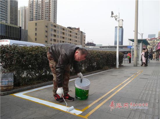 △施工人员在施划共享单车泊位。记者 王凯 摄