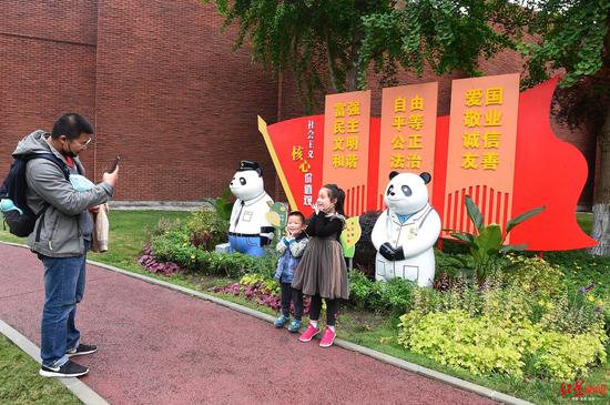 市民在绿道旁与熊猫雕塑合影留念