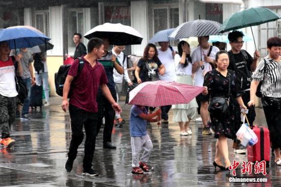 资料图:民众雨中出行。中新社记者 张远 摄