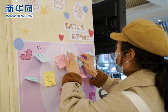 2月1日,一名結(jié)束醫(yī)學觀察的武漢滯留旅客離開定點服務(wù)酒店時在留言墻上寫下感謝的話。新華社記者 張超群 攝