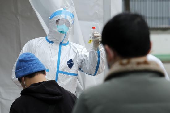 　12月10日，在郫都区中医医院核酸检测点，医务人员向居民介绍核酸检测注意事项。新华社记者 沈伯韩 摄