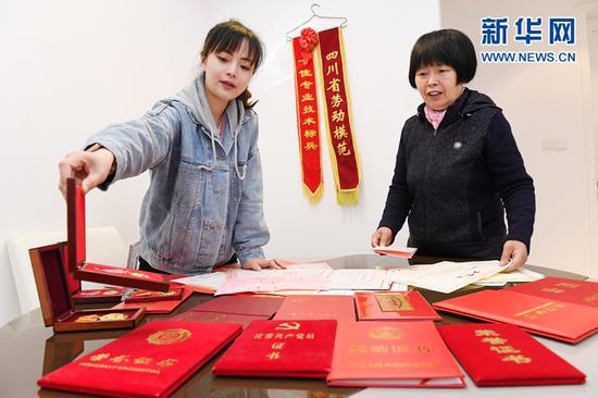 2021年3月4日,在成都市錦江區一小區,陳德智(左)把自己工作14年來獲得的各種證書交給母親保管。