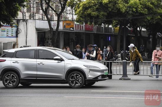 橫跨護欄穿越益州大道的行人等待車輛通行