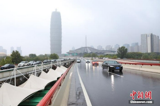 资料图:8月22日,河南省郑州市气象台发布暴雨红色预警信号。图为车辆在郑州一高架路行驶。 中新社记者 阚力 摄