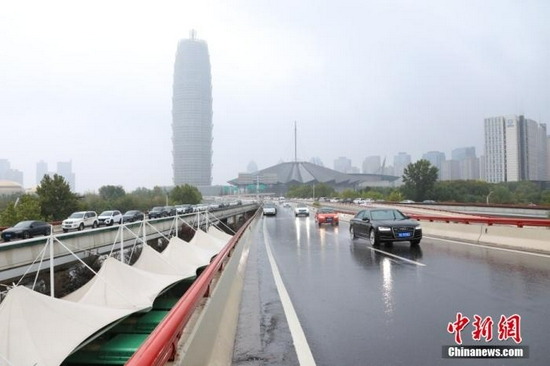 资料图：8月22日，河南省郑州市气象台发布暴雨红色预警信号。图为车辆在郑州一高架路行驶。 中新社记者 阚力 摄