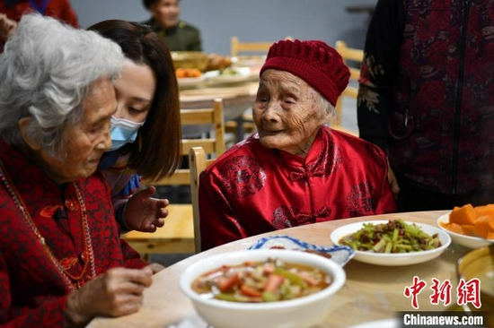 121岁的朱郑氏与百岁老人喻泽琴话家常。　张浪 摄