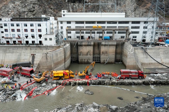 1月13日，救援人员用机械抽出丹巴县章谷镇三岔河关州电站厂的积水（无人机照片）。