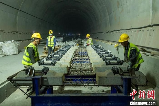 成自宜高铁龙泉山隧道内工人师傅们正在进行无砟轨排的吊装等作业。