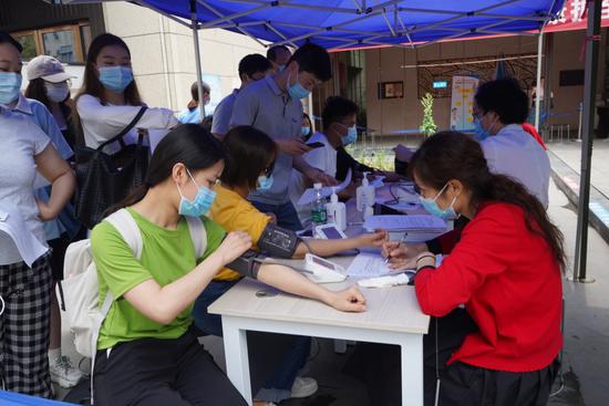 锦江区沙河街道新冠疫苗临时接种点，进入的居民要先测血压等。魏冯摄。