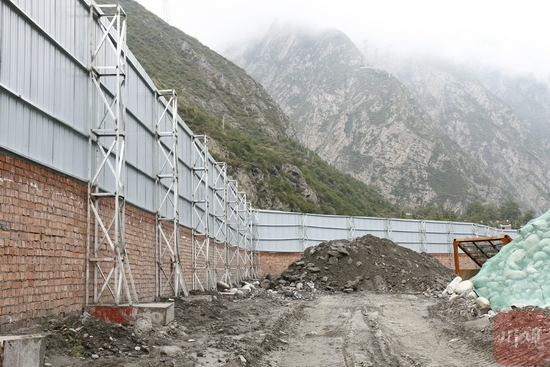 理县下孟砂石加工厂堆料场建起挡板屏障。