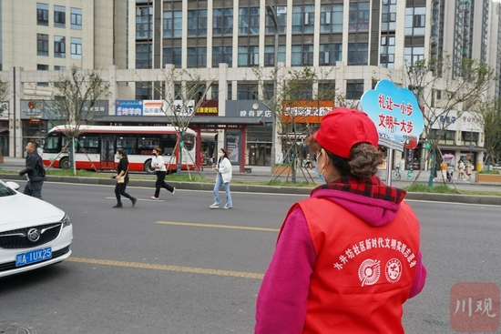 水井坊社区志愿者李大姐举牌劝导,还有行人乱穿行