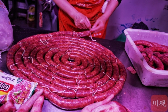 益民菜市场里的肉摊前,都在忙着灌香肠。