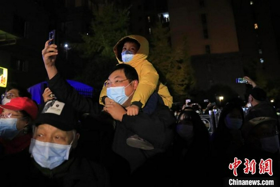 成都市民劉唯一背著兒子走出小區(qū)。 王磊 攝