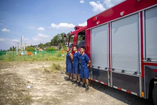 8月27日，留守的消防员们值守在消防车旁。