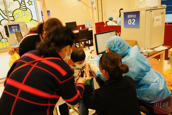 11月24日下午，在成都市武侯区簇锦街道新冠疫苗接种点一名小朋友正在接种，家长和幼儿园的老师正在安抚。魏冯摄。