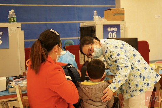 11月24日下午，在成都市武侯吾悦广场2楼，簇锦街道新冠疫苗接种点的情绪管理员李静正在现场安抚孩子。魏冯摄。