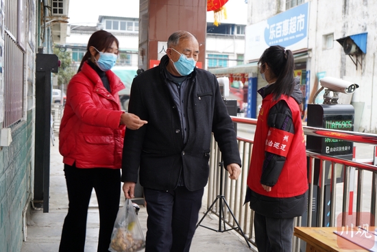 彭州市敖平镇兴平村金港湾小区，志愿者正在引导居民扫码、测温。魏冯 摄