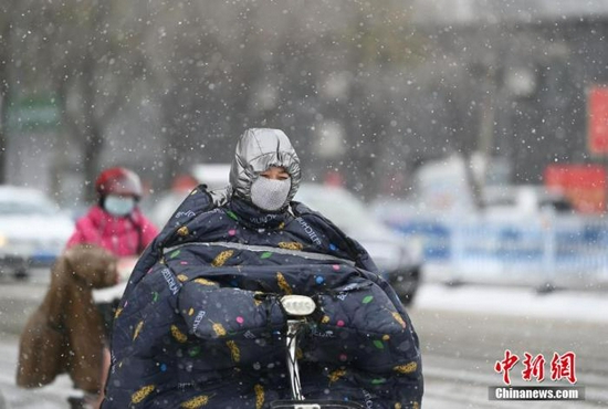 资料图：民众在雪中出行。 中新社记者 刘文华 摄