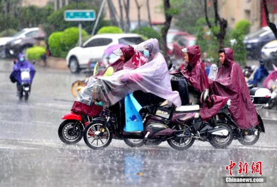 資料圖:市民在雨中出行。張斌 攝