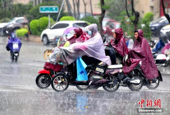 资料图：市民在雨中出行。张斌 摄