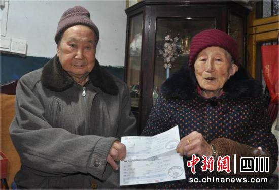 　王增印老人和老伴一起展示“四川省公益事业捐赠统一票据”。
