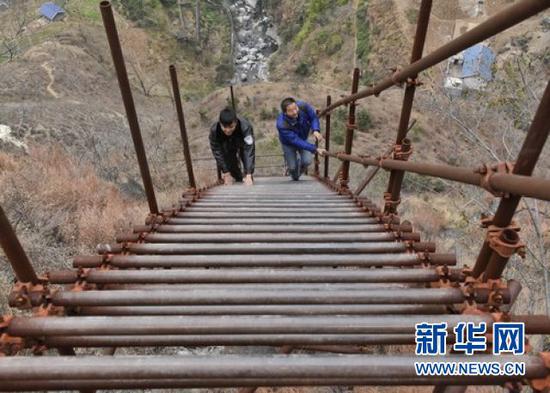谢杰(右)与同事一起登钢梯上瓦伍村。新华社记者刘坤摄