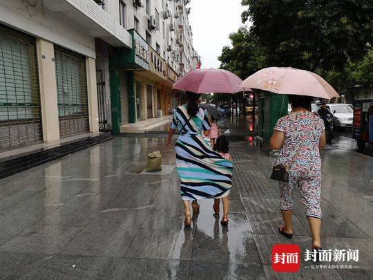 雨中最美背影:妈妈用红伞和裙子为女儿撑起一