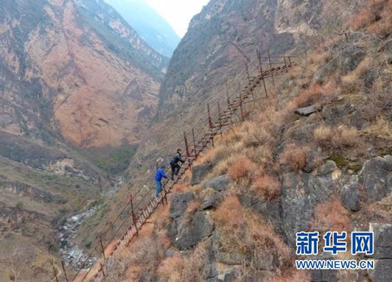 1月20日,谢杰(左)与同事一起登钢梯上瓦伍村。新华社记者刘坤摄