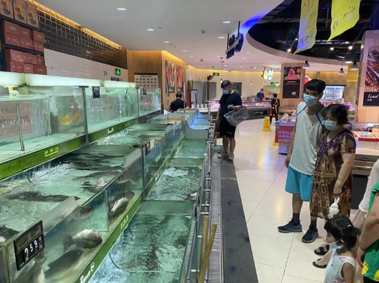 几名成都市民在永辉超市内选购淡水鱼。