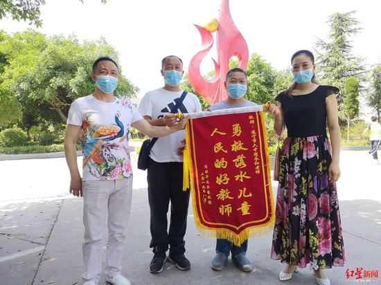 刘声华（左一）和妻子将锦旗送给周永红老师（左二）